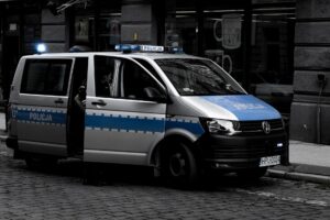 A police van parked on a cobblestone street in an urban setting. — atak w autobusie miejskim