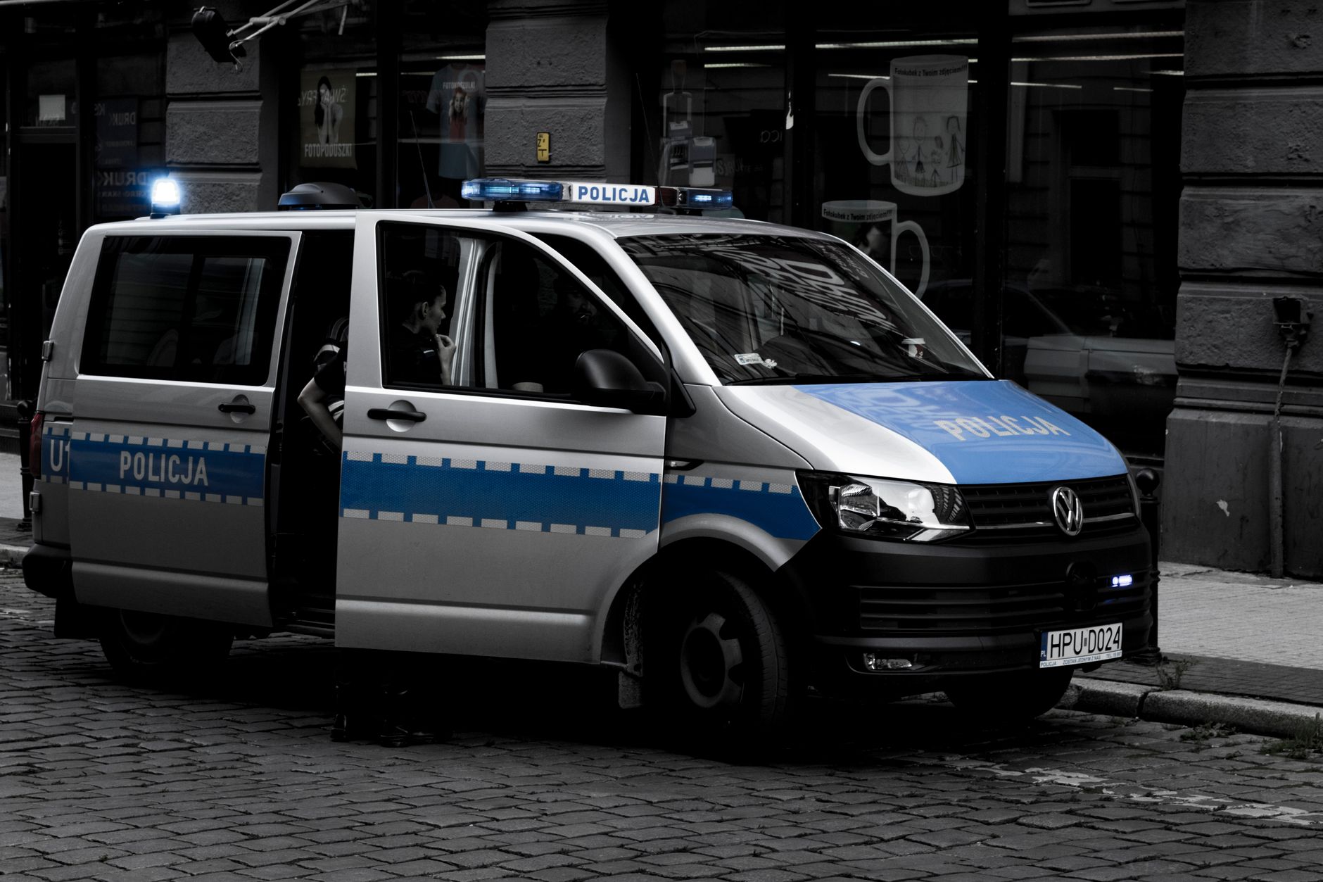 A police van parked on a cobblestone street in an urban setting. — atak w autobusie miejskim