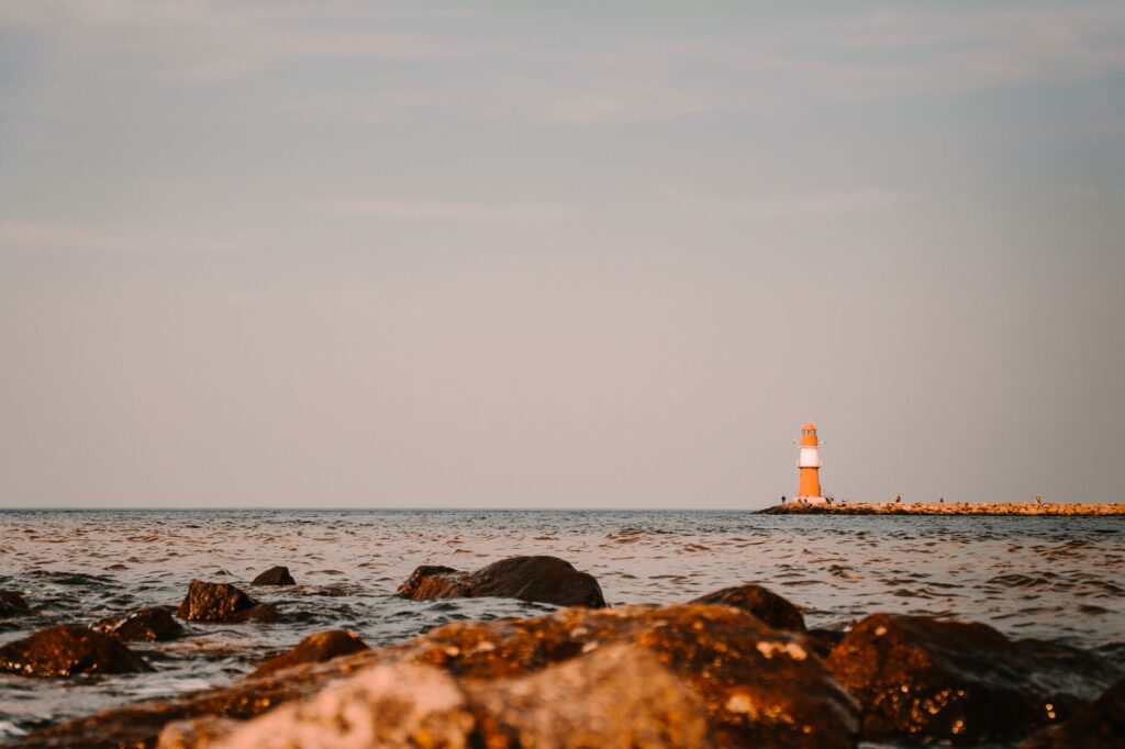 Scenic view of a lighthouse on the Baltic Sea coast in Rostock, Germany, with a rocky shoreline. — neutralizacja niewybuchów na Bałtyku