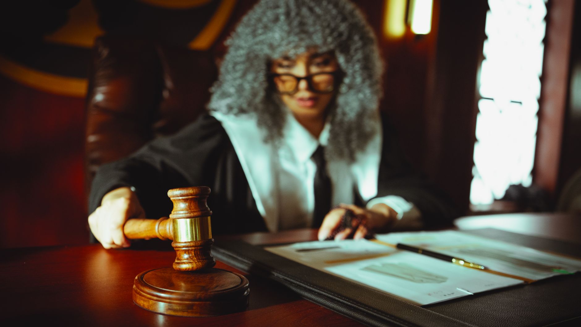 Female judge in a courtroom setting, focusing on legal documents with a gavel. — Polski Komitet Olimpijski śledztwo