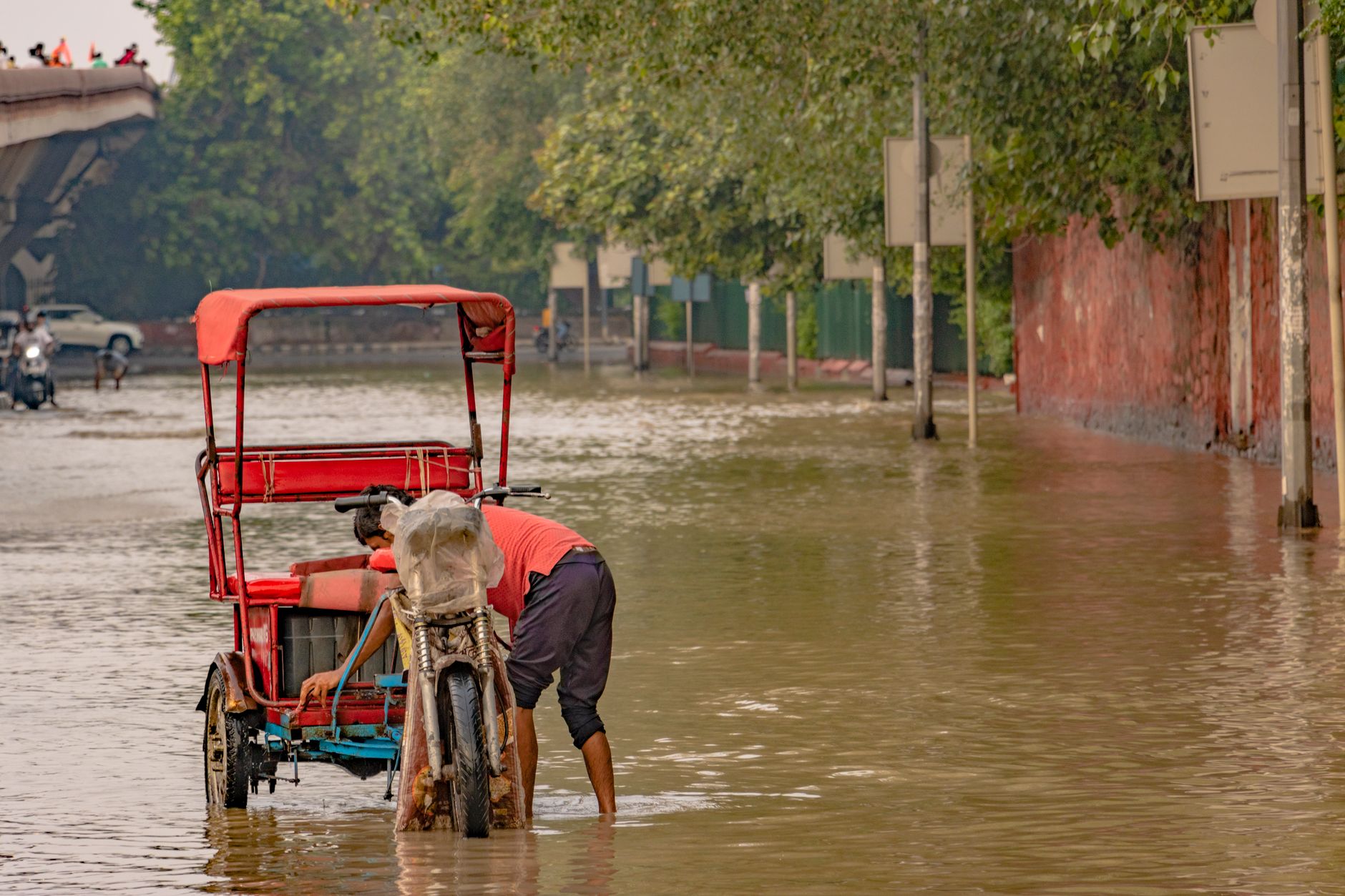 A rickshaw navigates a flooded street in New Delhi, India, during the 2023 monsoon. — powódź w Nepalu akcja ratunkowa
