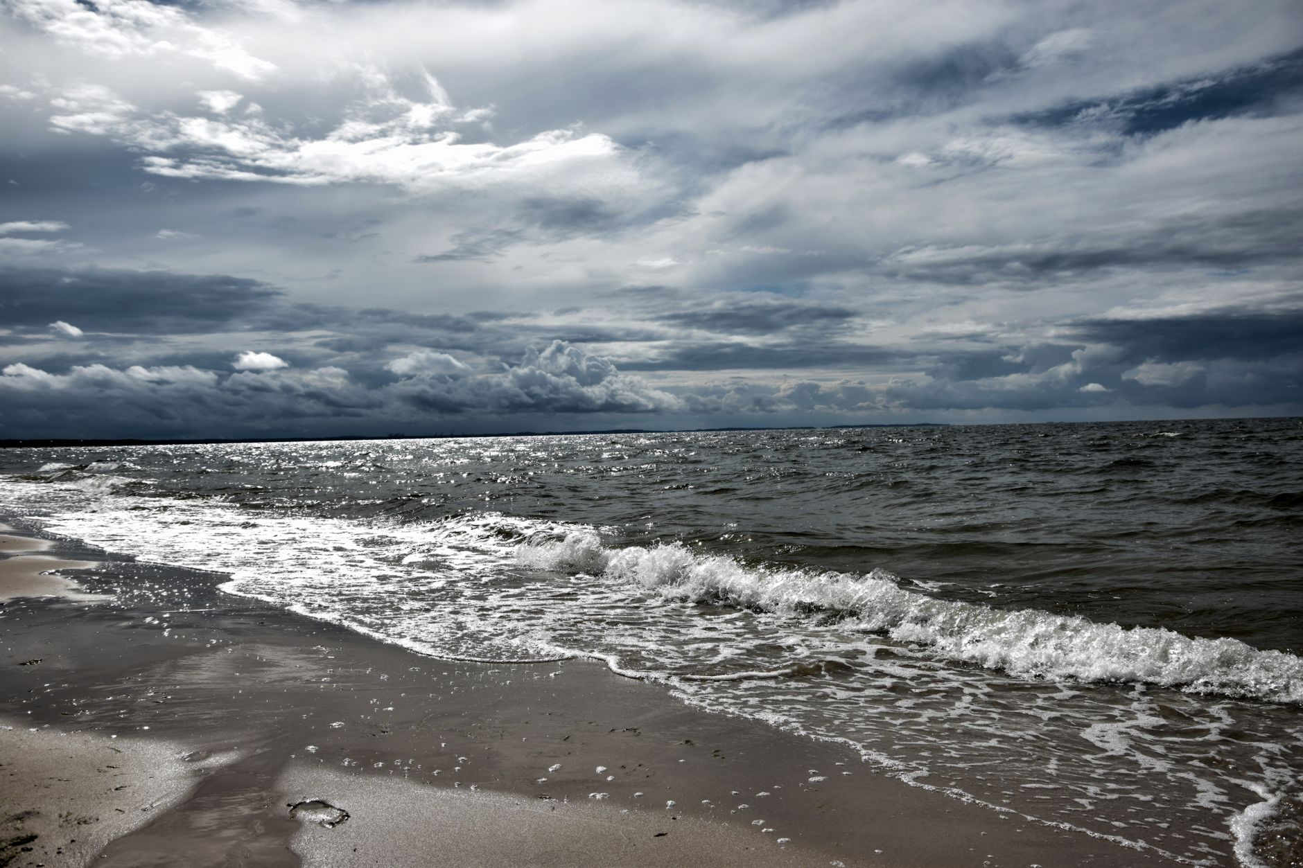 A dramatic view of a sandy beach with stormy clouds and waves crashing on the shore. — spotkanie młodzieży w Juracie