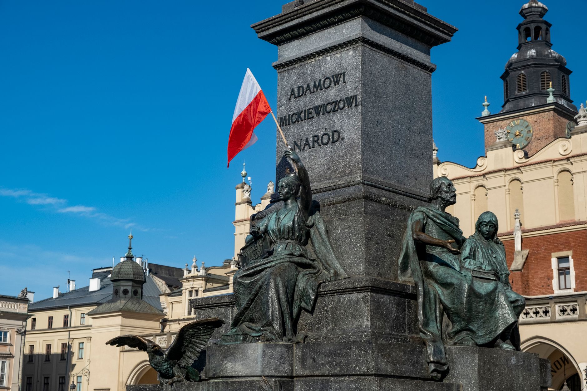 Monument of Adam Mickiewicz in Kraków, featuring Polish flag and historic architecture. — wybory w Krakowie