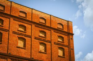 Low angle view of a historic red brick building in Łódź, Poland against a blue sky. — incydenty w łódzkich szkołach