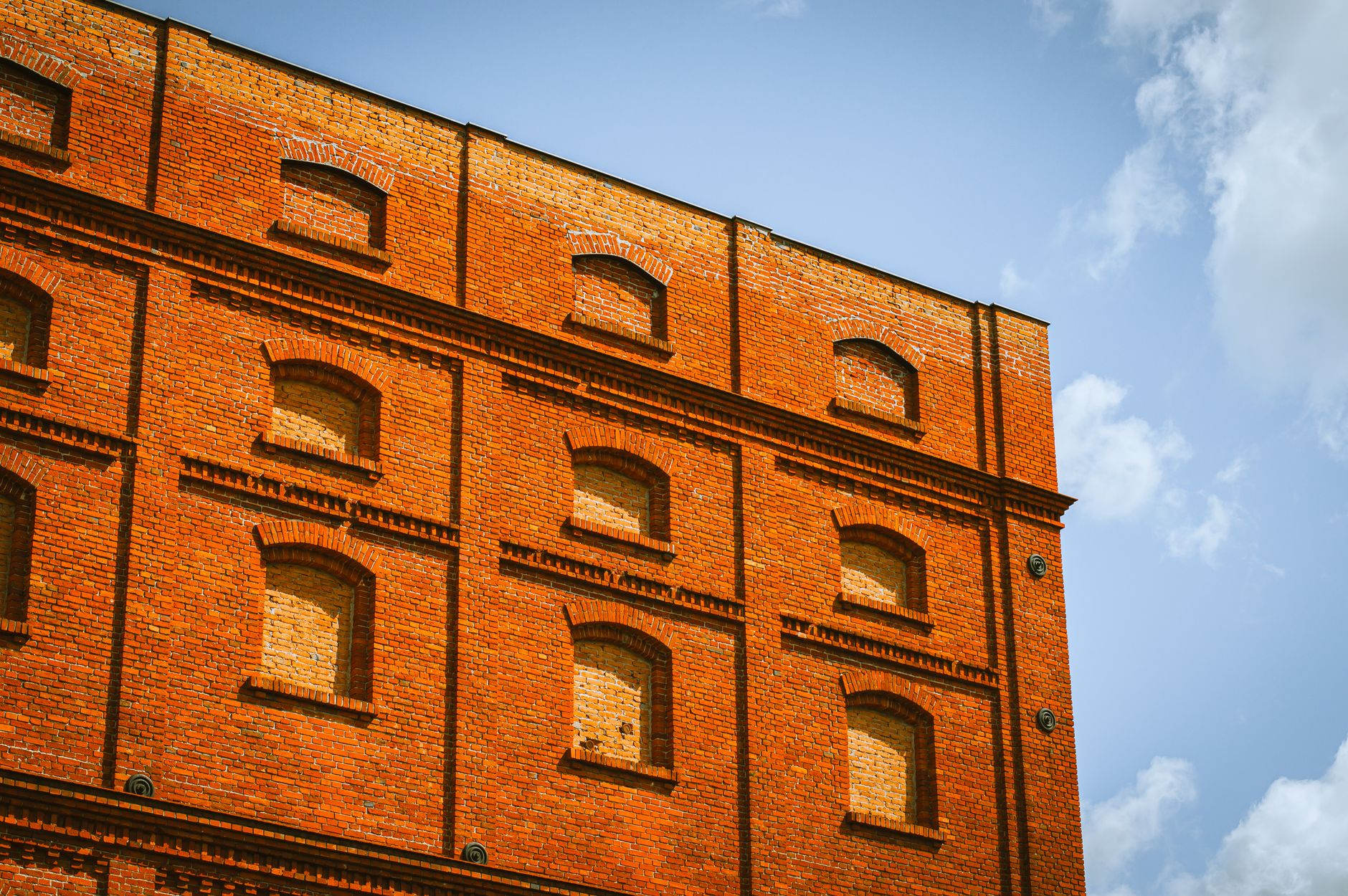 Low angle view of a historic red brick building in Łódź, Poland against a blue sky. — incydenty w łódzkich szkołach