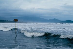 Cloudy coastal scene with warning sign and waves crashing against the shore, conveying sea caution. — trzęsienie ziemi w Panamie