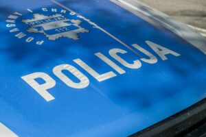 Detailed image of a Polish police car hood showing insignia and text 'Policja'. — potrącenie na pasach w Piastowie