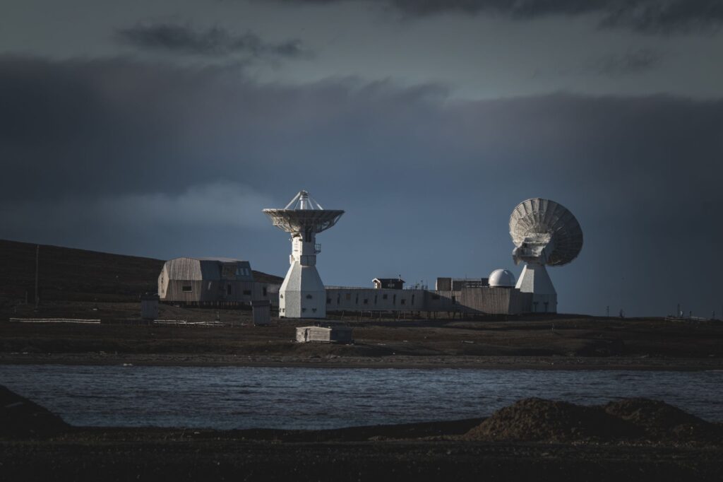 A remote satellite station with large dishes stands under a moody dark sky by the water. — infrastruktura satelitarna Starlink