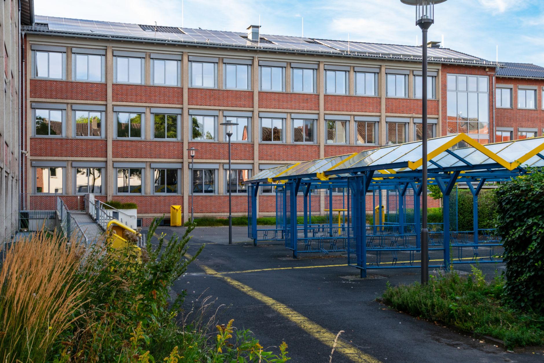 School building with solar panels, blue bicycle racks, and greenery. Sunny day. — atak w szkole na Słowacji