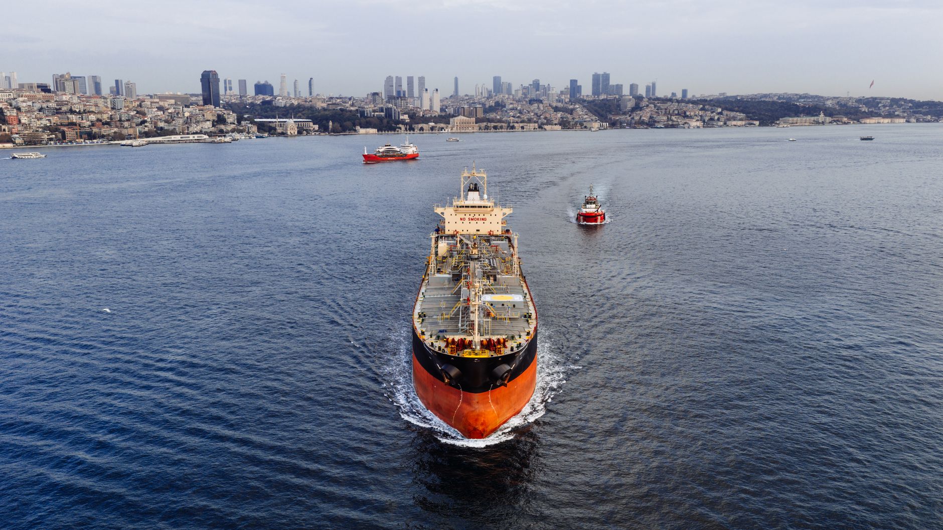 A stunning aerial shot of a cargo ship navigating the Bosphorus Strait in Istanbul, Turkey, with a city — Cieśnina Ormuz
