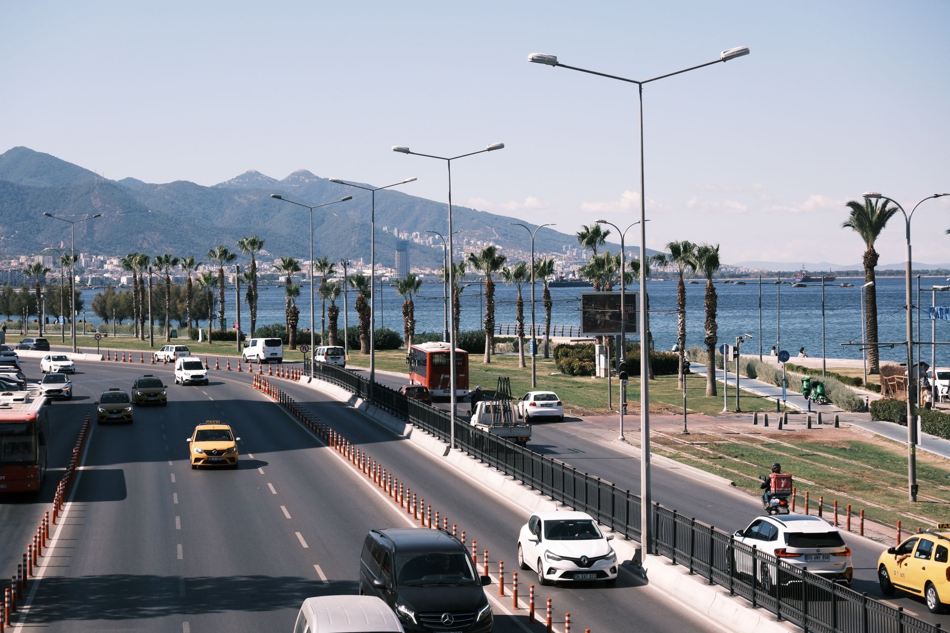 Daytime city traffic along the scenic seafront highway in Izmir, Turkey, with mountain views. — wypadek autokaru w Turcji